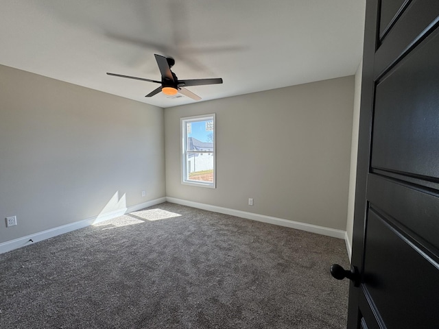 carpeted spare room featuring ceiling fan and baseboards