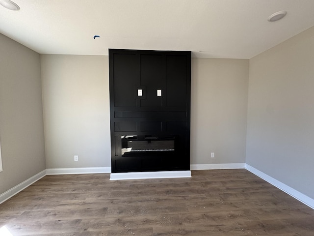 unfurnished living room featuring baseboards and wood finished floors