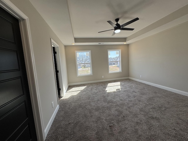 unfurnished bedroom with a raised ceiling, carpet flooring, baseboards, and ceiling fan