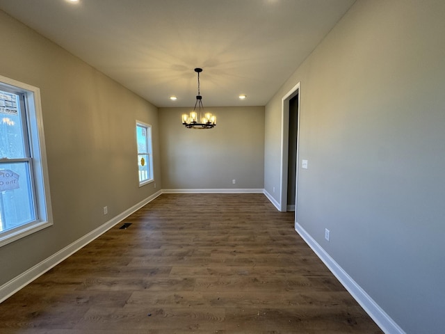 unfurnished dining area with visible vents, dark wood-type flooring, recessed lighting, baseboards, and a chandelier