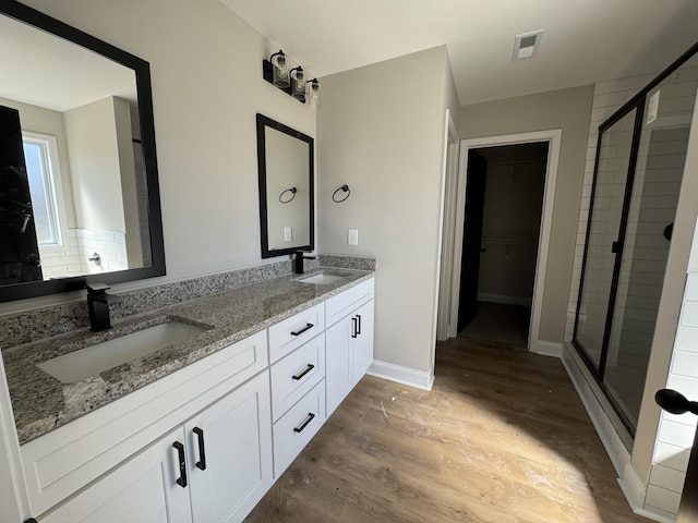 full bath featuring a shower stall, wood finished floors, and a sink