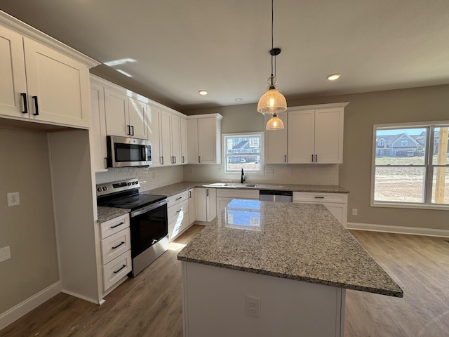 kitchen featuring decorative backsplash, white cabinets, stainless steel appliances, and wood finished floors