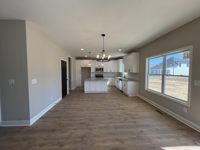 kitchen featuring baseboards, an inviting chandelier, dark wood-style flooring, appliances with stainless steel finishes, and white cabinetry