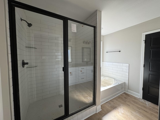 full bath featuring a stall shower, baseboards, wood finished floors, and a bath