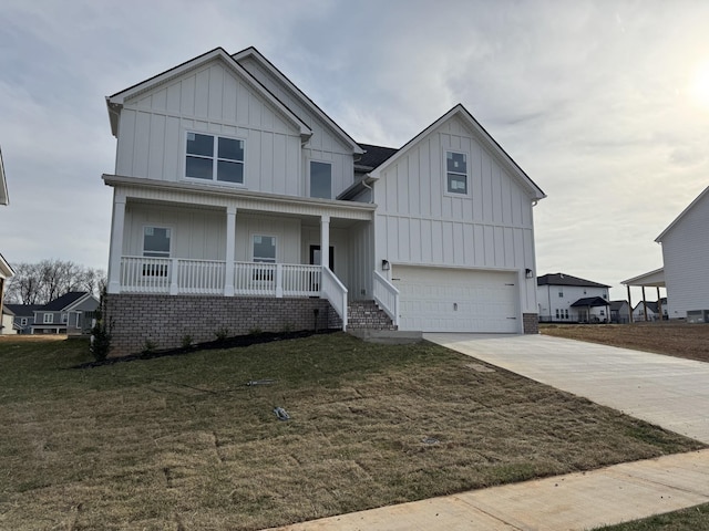 view of front of home with driveway, covered porch, board and batten siding, an attached garage, and a front yard