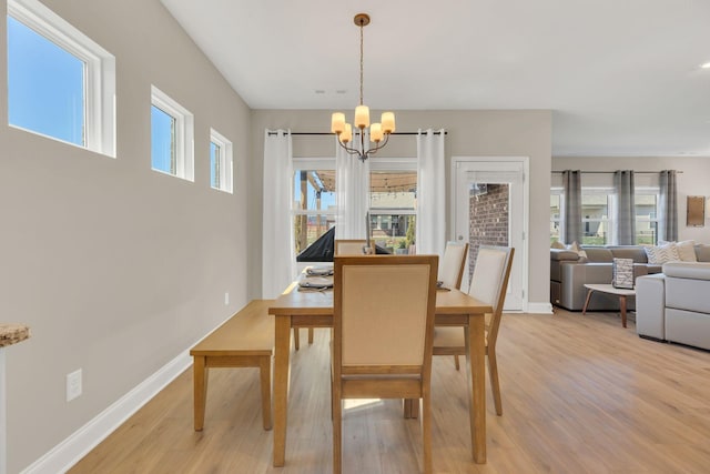 dining room with baseboards, a notable chandelier, and light wood-style flooring