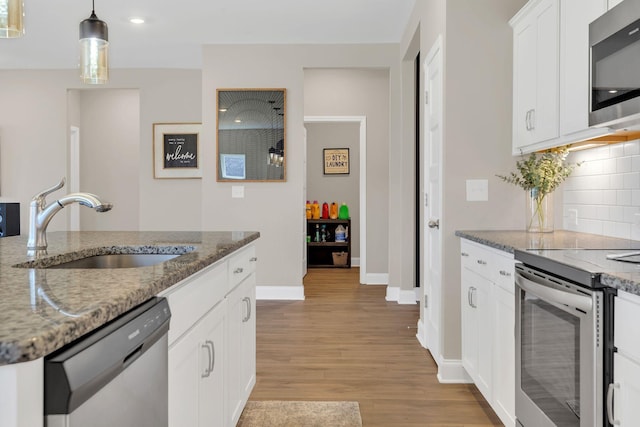 kitchen with light stone countertops, decorative backsplash, light wood-style flooring, appliances with stainless steel finishes, and a sink