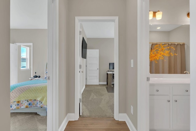 corridor with wood finished floors, carpet, and baseboards