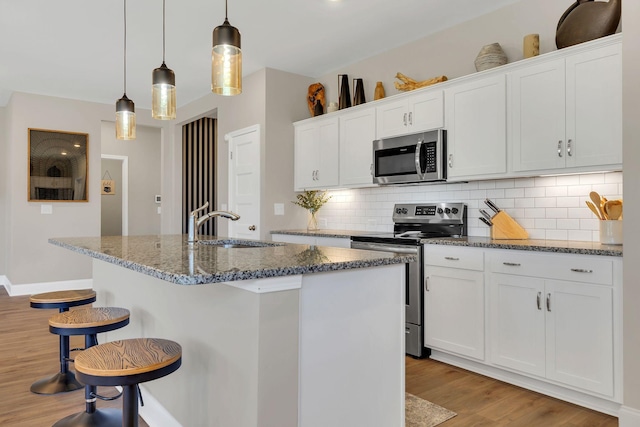 kitchen with light wood-type flooring, stainless steel appliances, backsplash, and white cabinets