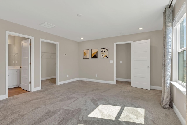 unfurnished bedroom featuring visible vents, light carpet, multiple windows, and a spacious closet