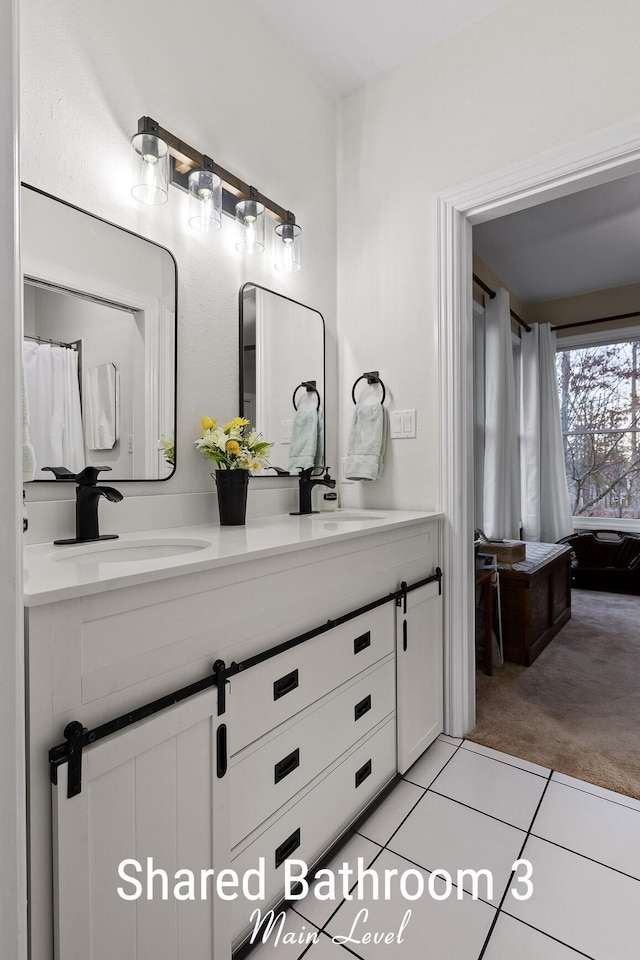 full bath featuring tile patterned flooring, double vanity, and a sink