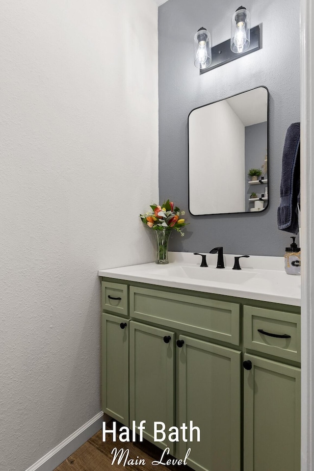 bathroom featuring baseboards, wood finished floors, vanity, and a textured wall