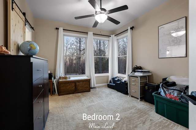 interior space with light colored carpet, a barn door, and ceiling fan