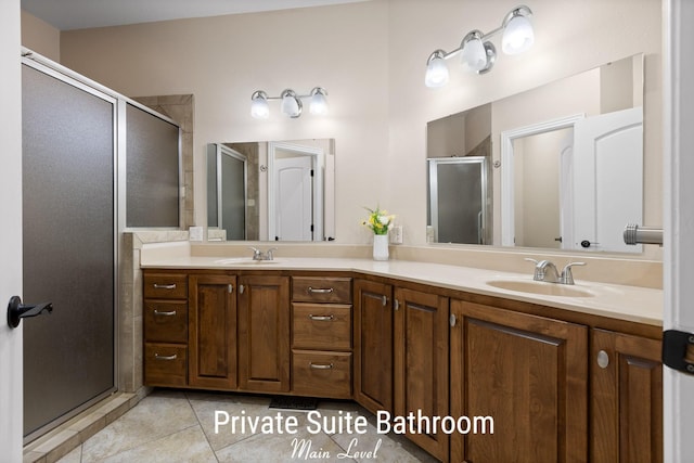 bathroom with tile patterned flooring, a shower stall, double vanity, and a sink