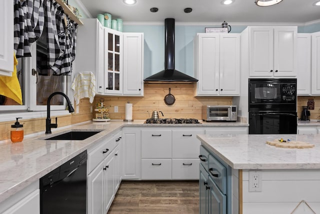 kitchen featuring ornamental molding, a sink, black appliances, white cabinetry, and wall chimney exhaust hood