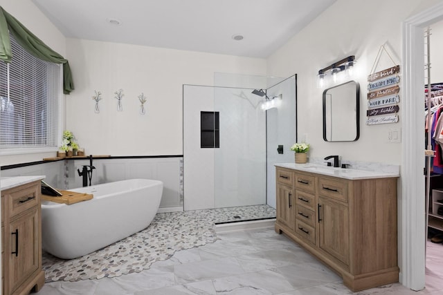 bathroom with a wainscoted wall, marble finish floor, a walk in shower, a freestanding bath, and vanity