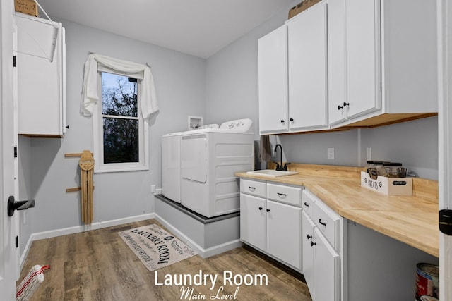 laundry room featuring cabinet space, washer and dryer, wood finished floors, and a sink