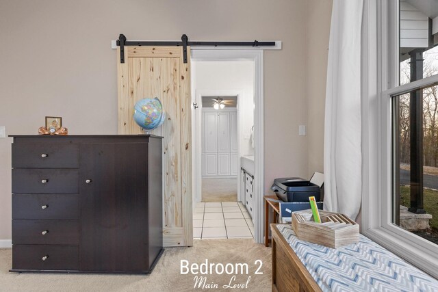 bedroom featuring light tile patterned floors, light colored carpet, and ensuite bath