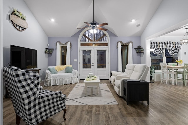 living area with french doors, ceiling fan with notable chandelier, wood finished floors, and vaulted ceiling