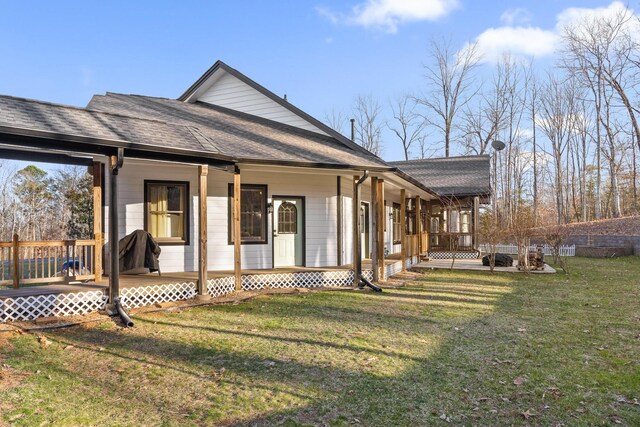 rear view of property with covered porch, a shingled roof, and a yard