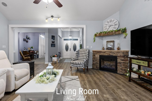 living room with a stone fireplace, wood finished floors, baseboards, and a ceiling fan