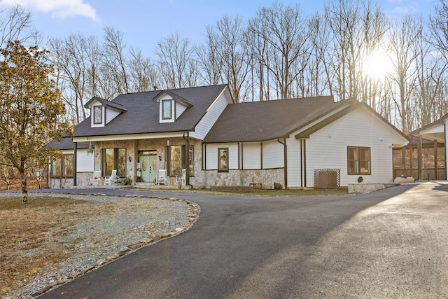 view of front of house featuring aphalt driveway, stone siding, and a shingled roof