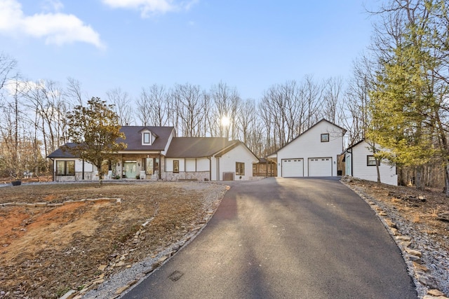 view of front of home featuring aphalt driveway, a garage, and an outdoor structure