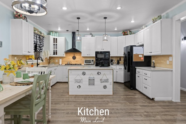 kitchen with white cabinets, black appliances, wall chimney range hood, and wood finished floors