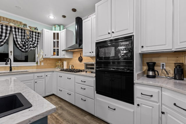 kitchen with gas cooktop, dark wood-style floors, a sink, white cabinetry, and wall chimney range hood