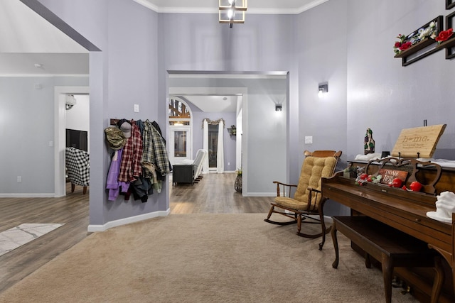 carpeted foyer with baseboards, a high ceiling, wood finished floors, and crown molding