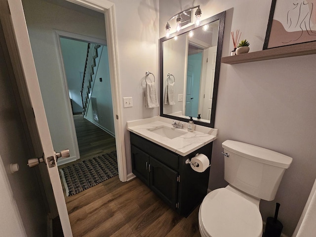 bathroom with toilet, vanity, baseboards, and wood finished floors