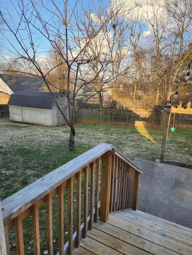 wooden terrace with a storage shed, an outbuilding, a lawn, and a fenced backyard