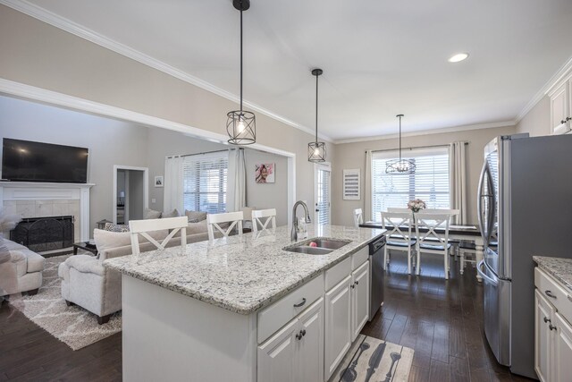 kitchen with a sink, dark wood-style floors, white cabinetry, appliances with stainless steel finishes, and a tile fireplace