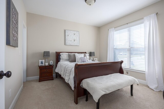 bedroom with light colored carpet and baseboards