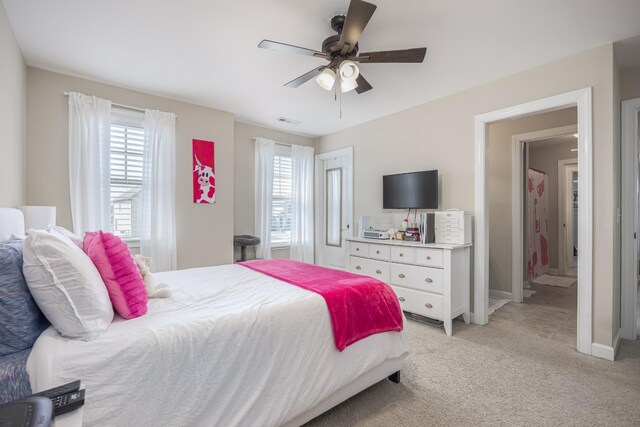 bedroom with ceiling fan, multiple windows, visible vents, and light carpet