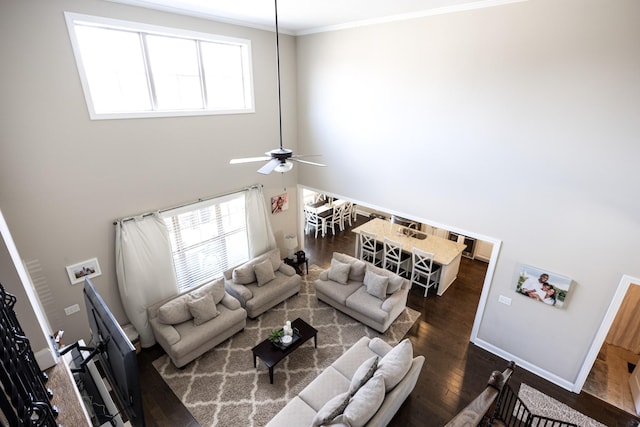 living room featuring baseboards, a healthy amount of sunlight, ornamental molding, and dark wood-style flooring