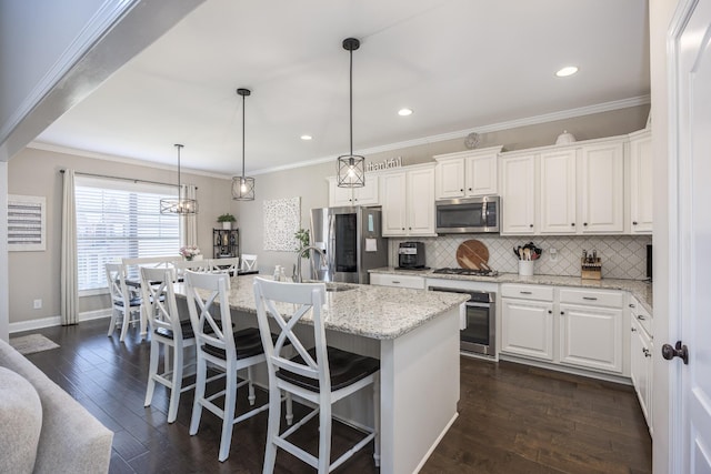 kitchen with tasteful backsplash, white cabinets, appliances with stainless steel finishes, and dark wood finished floors