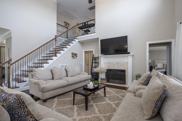 living room featuring a high ceiling, wood finished floors, stairs, and a tile fireplace