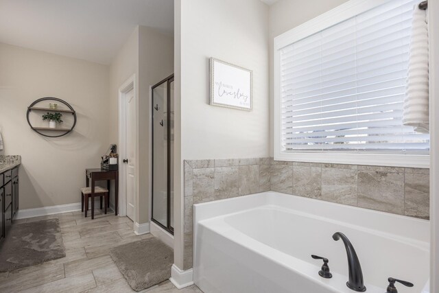 bathroom featuring baseboards, a stall shower, vanity, and a garden tub