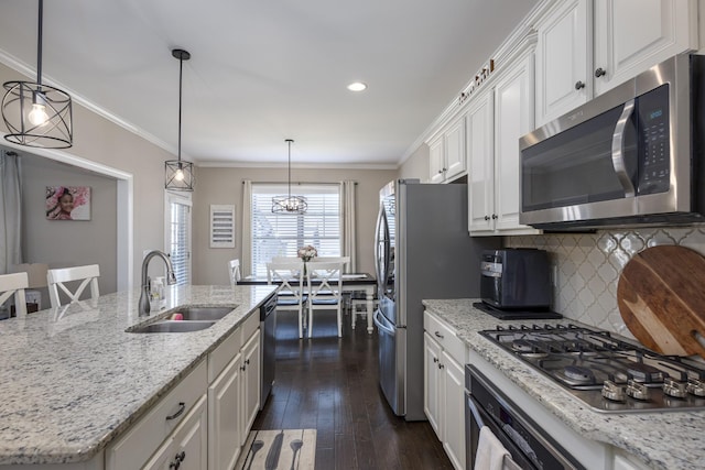 kitchen with ornamental molding, dark wood-style floors, white cabinets, stainless steel appliances, and a sink