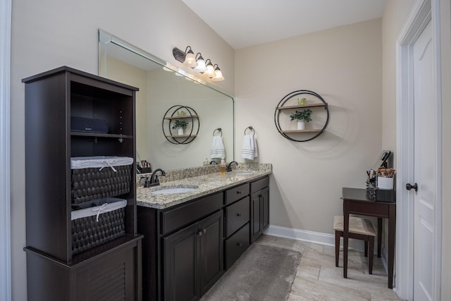 bathroom featuring double vanity, baseboards, and a sink