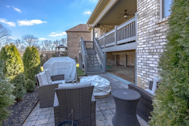 view of patio / terrace with a deck, a ceiling fan, an outdoor living space, grilling area, and stairs