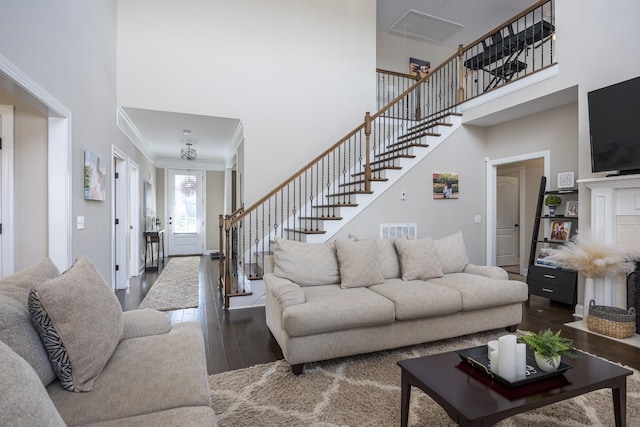 living area with visible vents, stairs, a high ceiling, and wood finished floors