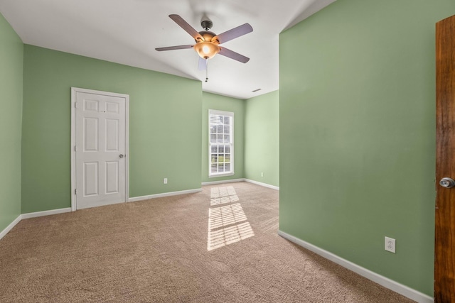 carpeted empty room featuring a ceiling fan and baseboards