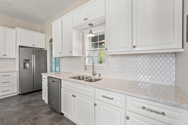 kitchen with a sink, light stone counters, stainless steel appliances, white cabinets, and decorative backsplash