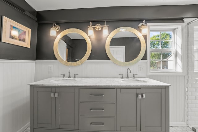 bathroom featuring a sink, double vanity, and wainscoting