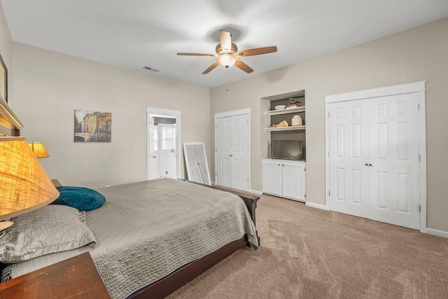 carpeted bedroom featuring visible vents, ceiling fan, baseboards, and multiple closets