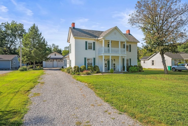 view of front of property with an outbuilding, a balcony, covered porch, a front lawn, and a garage