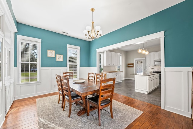 dining space featuring visible vents, a notable chandelier, a healthy amount of sunlight, and dark wood-style flooring