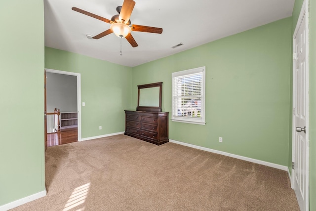 unfurnished bedroom with a ceiling fan, carpet, visible vents, and baseboards